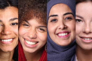 A composite image showing close-up portraits of four smiling women of diverse backgrounds, each representing different ethnicities and styles, arranged side by side.