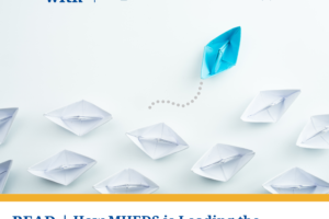 A blue paper boat leads a group of white paper boats in a different direction. Text: Erie thrives with MHEDS. Read now: How MHEDS is leading the charge for systemic change in the region’s healthcare and beyond.