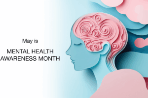 A stylized illustration of a woman’s head in blue with pink swirls representing the brain, alongside text that reads “May is MENTAL HEALTH AWARENESS MONTH” on a white and pastel background.
