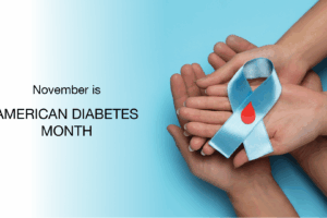 Several hands hold a blue ribbon with a red drop, symbolizing diabetes awareness, next to the text: November is American Diabetes Month on a blue and white background.